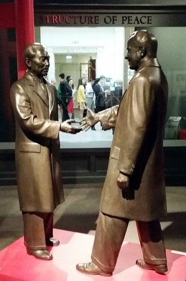 Life-size bronze figures of Zhou Enlai and President Nixon shake hands at the center of the Nixon Library in California.